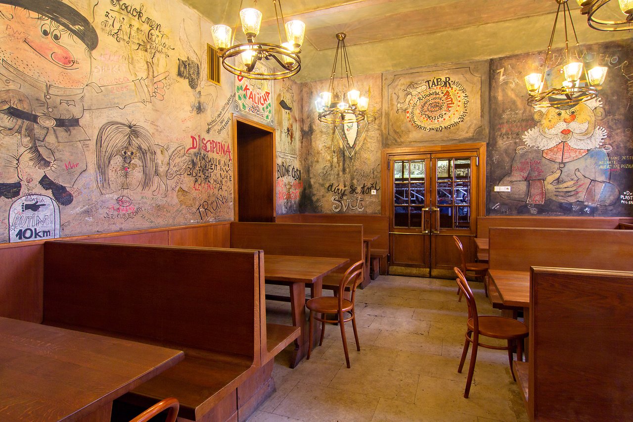 The interior of a brasserie with wooden tables and walls covered in drawings