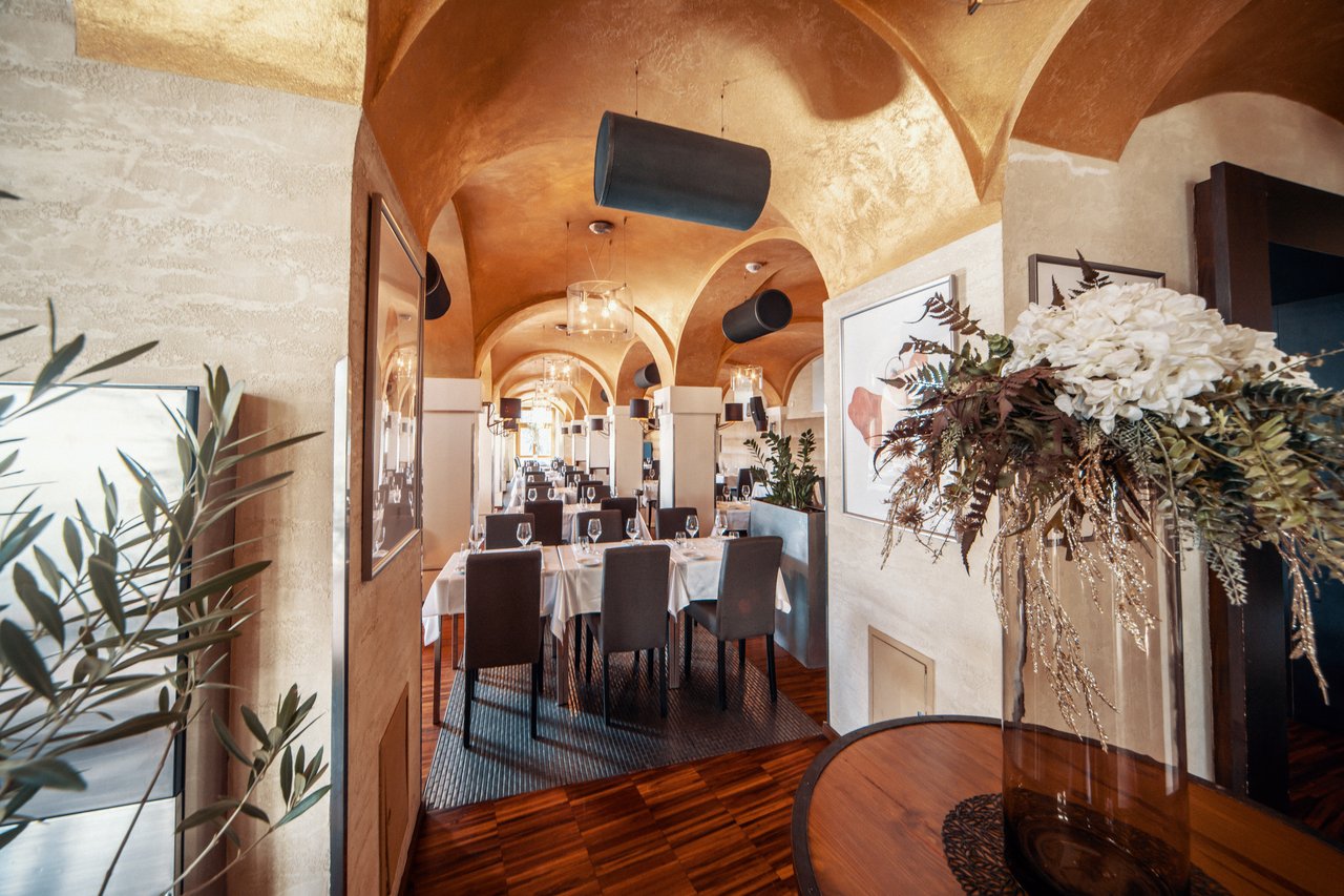 A dining room with a vaulted ceiling and a vase of flowers on a table