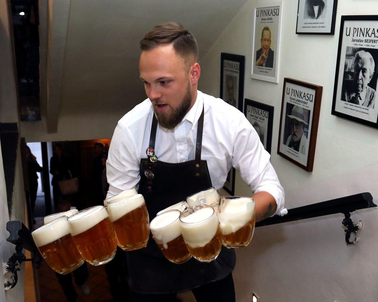 A waiter carrying several glasses of beer in both hands