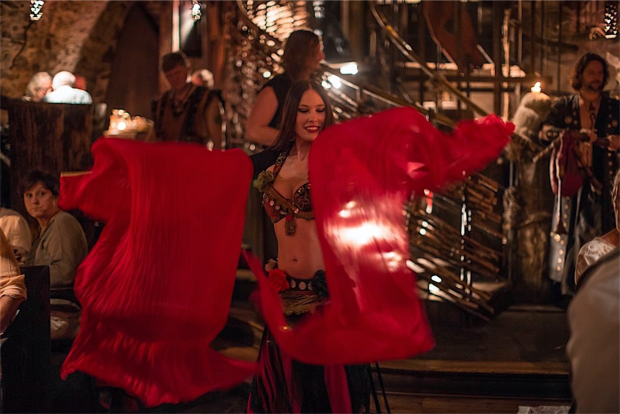 A woman in a medieval costume dancing with red scarves