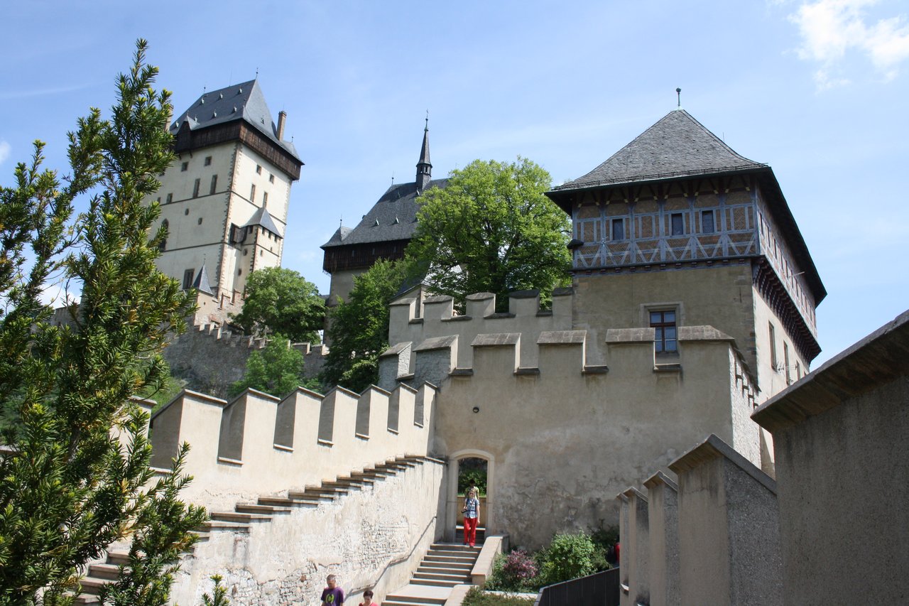 The castle's fortified ramparts and medieval towers, surrounded by greenery under a blue sky.